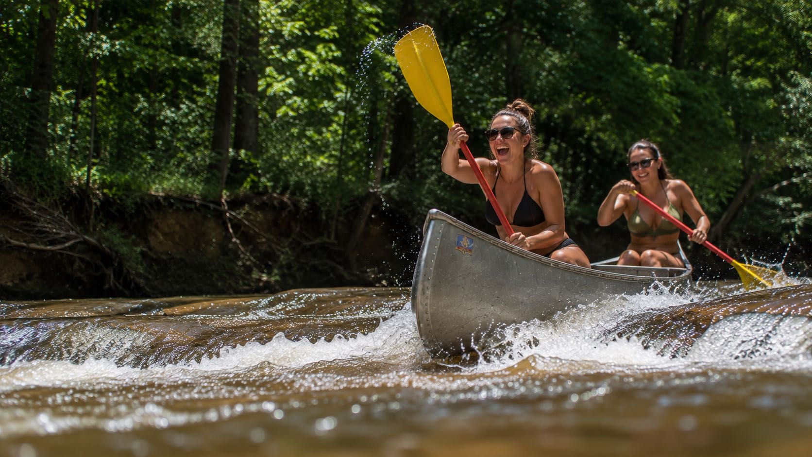 Two paddlers running a shoal in an aluminium canoe, photographed from water level